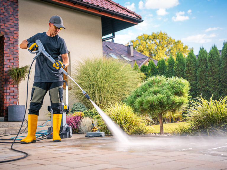 a-man-power-washing-a-patio-on-a-sunny-day-in-a-we-2025-03-15-23-05-57-utc